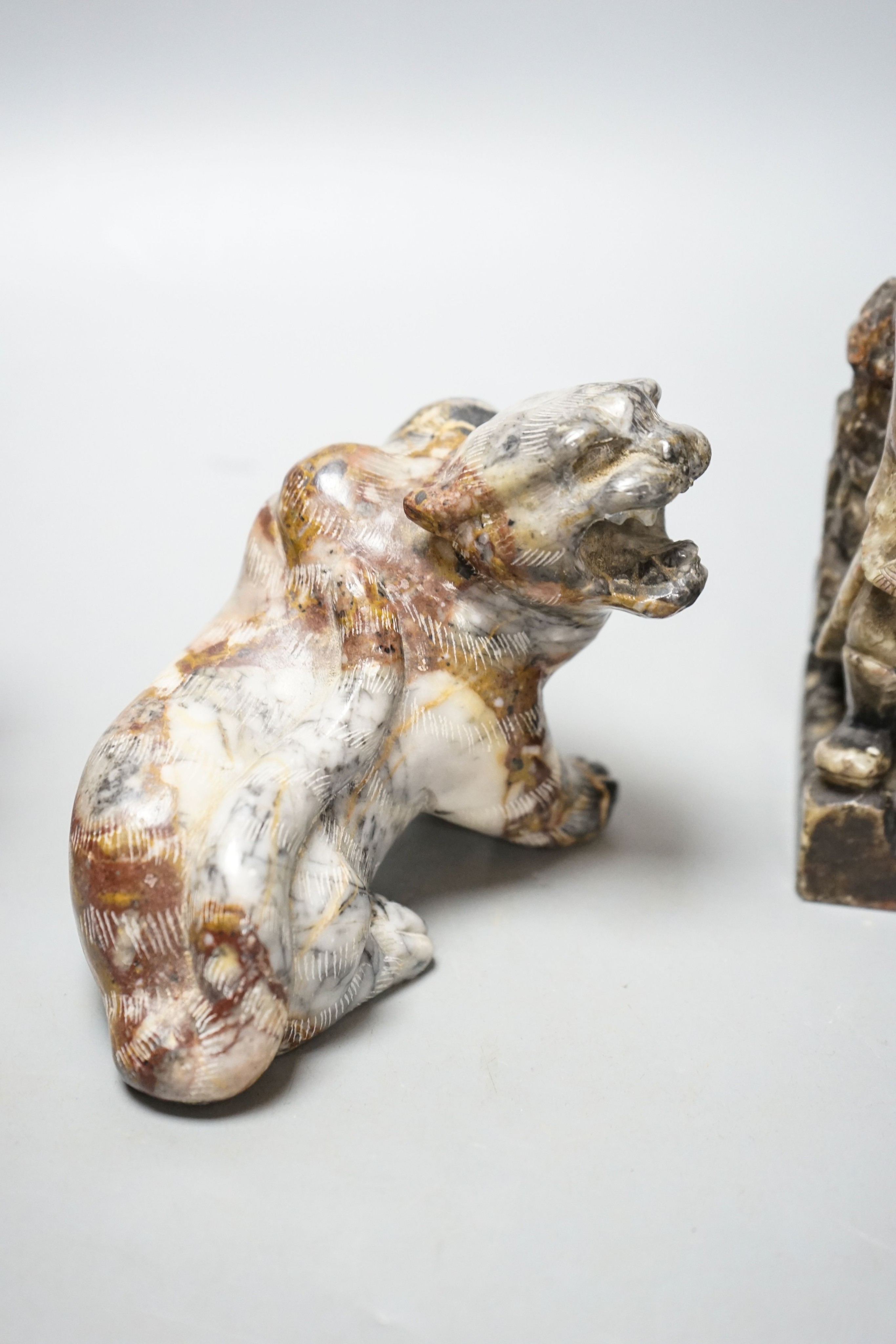 A pair of Chinese soapstone figures of immortals, modelled seated on rocky bases and a similar figure of tiger, 12cm